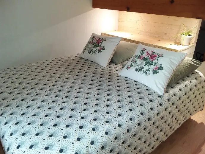 Lit double confortable avec couverture à motifs et oreillers floraux dans la chambre 'MAKILA' à la maison d'hôtes GOITIK IKUSITA.