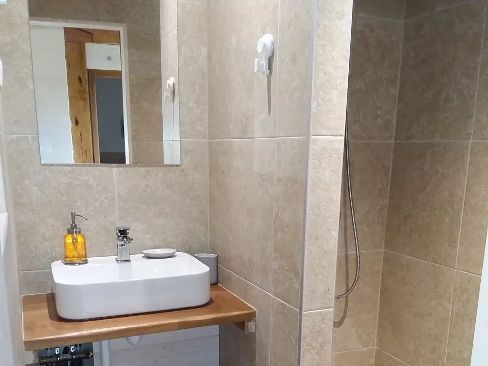 Salle de bain moderne de la chambre 'MAKILA' avec lavabo rectangulaire sur plan en bois, miroir et douche à l'italienne chez GOITIK IKUSITA