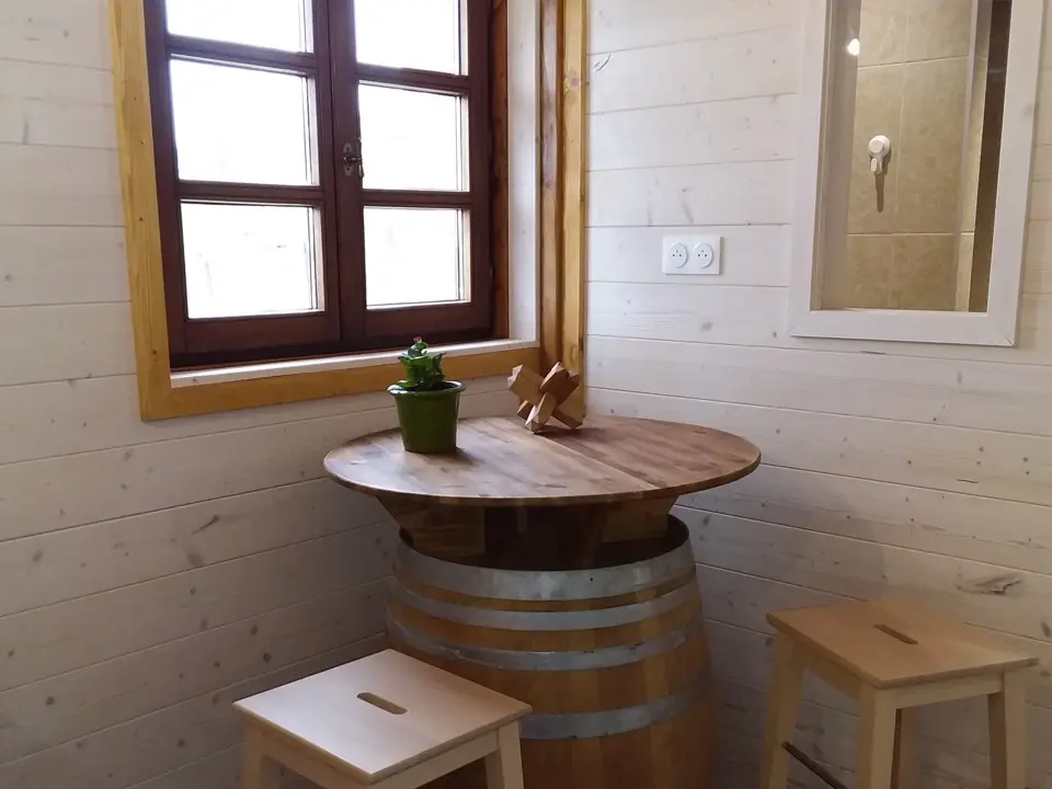 Coin de détente rustique avec table ronde sur tonneau et tabourets en bois dans la chambre 'MAKILA', invitant à la relaxation chez GOITIK IKUSITA.